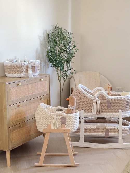 Nursery room with wooden dresser, wicker crib, and baby toys.